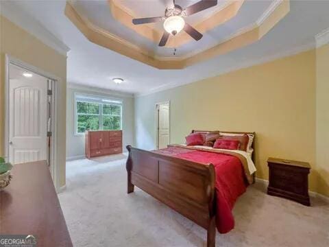 carpeted bedroom with a tray ceiling, ceiling fan, and crown molding