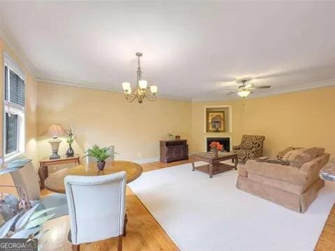 living room with ceiling fan with notable chandelier and light hardwood / wood-style flooring