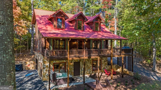 log-style house with a deck, a patio, and a hot tub