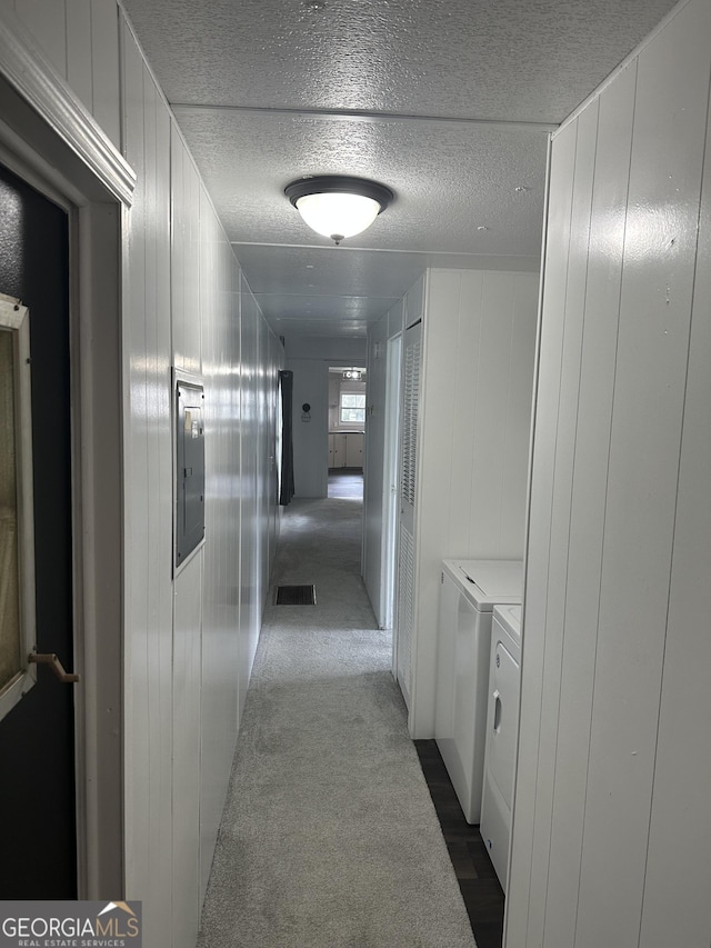 hallway featuring washer and dryer, dark carpet, and wooden walls