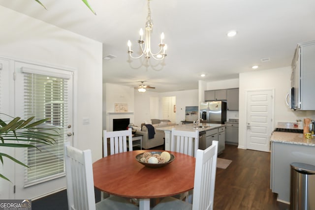 dining area featuring ceiling fan with notable chandelier, dark hardwood / wood-style floors, and sink