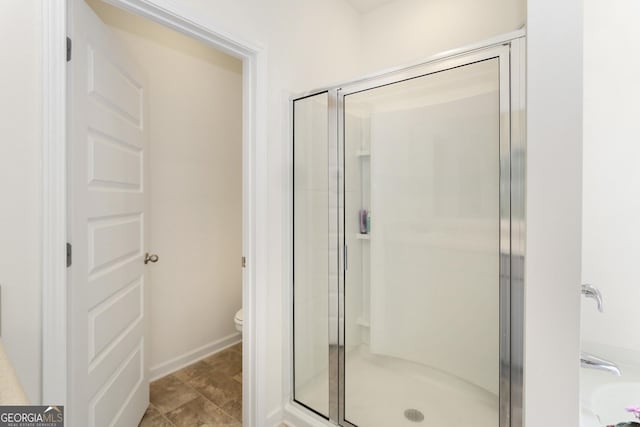 bathroom featuring a shower with shower door and toilet