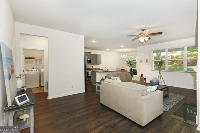 living room with ceiling fan with notable chandelier, sink, separate washer and dryer, and dark wood-type flooring