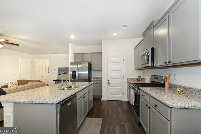 kitchen with gray cabinetry, dark wood-type flooring, sink, an island with sink, and stainless steel appliances