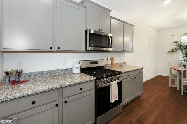 kitchen with light stone countertops, appliances with stainless steel finishes, and gray cabinetry