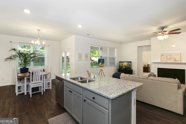 kitchen with ceiling fan with notable chandelier, sink, decorative light fixtures, dishwasher, and an island with sink