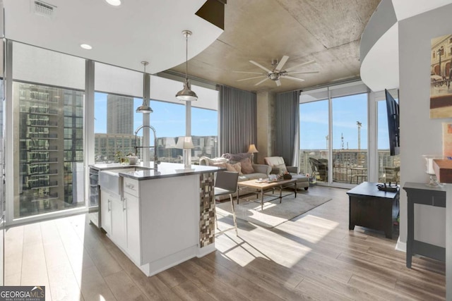 kitchen with floor to ceiling windows, ceiling fan, pendant lighting, light hardwood / wood-style floors, and white cabinets