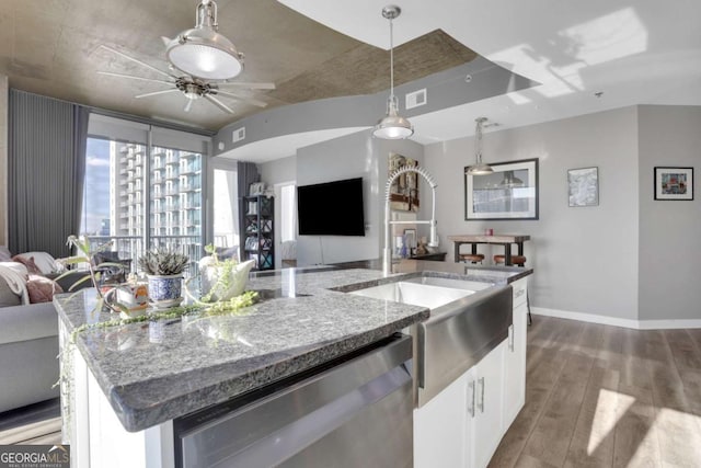 kitchen with white cabinets, stainless steel dishwasher, an island with sink, decorative light fixtures, and light stone counters