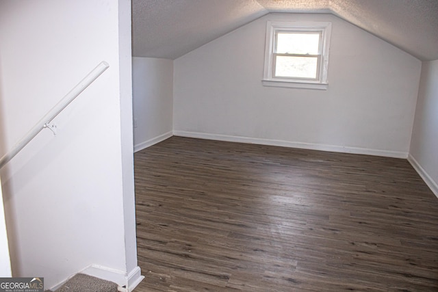 bonus room with dark hardwood / wood-style floors, a textured ceiling, and vaulted ceiling