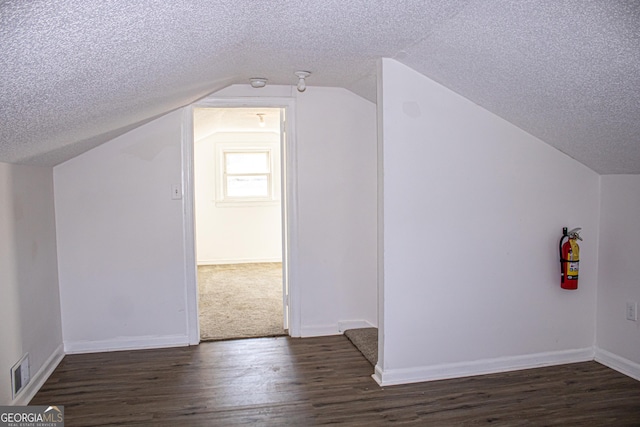 bonus room with a textured ceiling, dark hardwood / wood-style floors, and lofted ceiling