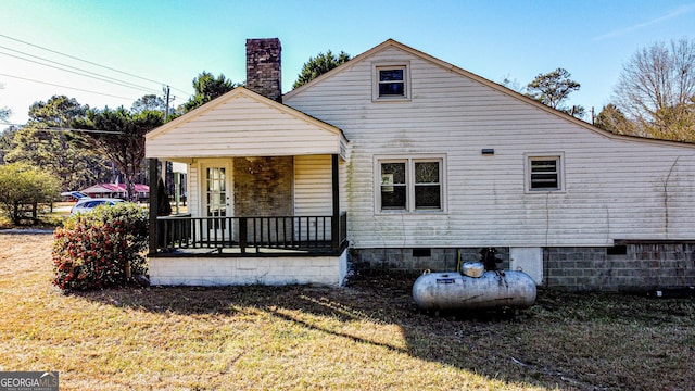 rear view of property featuring a yard and covered porch