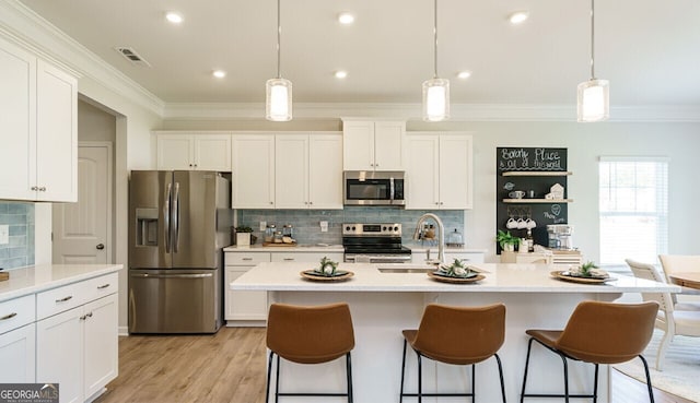 kitchen with sink, a center island with sink, decorative light fixtures, and appliances with stainless steel finishes