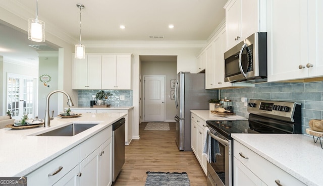 kitchen featuring sink, white cabinetry, stainless steel appliances, and hanging light fixtures