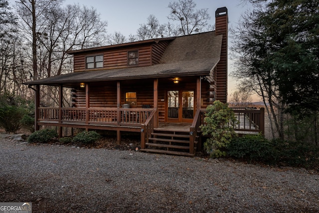 log-style house featuring a shingled roof, french doors, a chimney, and log siding