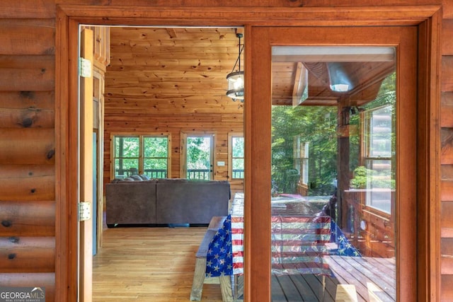 doorway to outside with log walls and light hardwood / wood-style floors