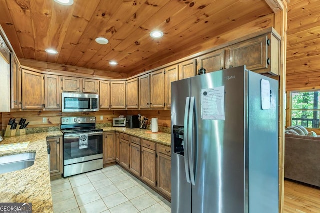 kitchen with light stone countertops, stainless steel appliances, sink, light tile patterned floors, and wooden ceiling