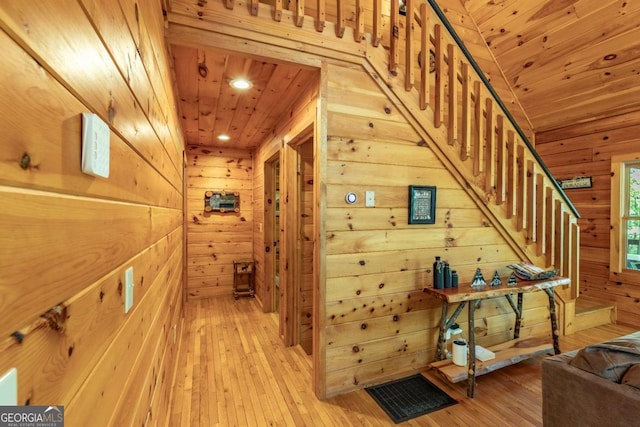 hallway featuring light hardwood / wood-style flooring, wooden walls, and wood ceiling