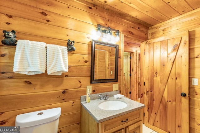 bathroom featuring vanity, wood walls, and toilet