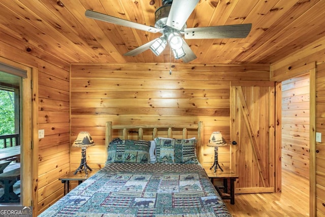 bedroom featuring ceiling fan, wood walls, light wood-type flooring, and wooden ceiling