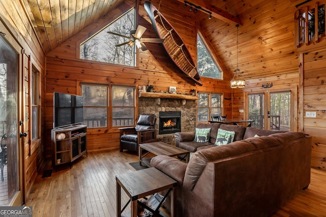 living room with wood ceiling, a stone fireplace, wooden walls, and hardwood / wood-style flooring