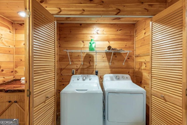 washroom with washing machine and clothes dryer and wood walls