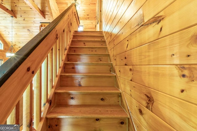 staircase featuring beam ceiling, wood ceiling, and wooden walls