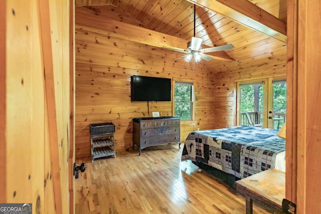 bedroom with hardwood / wood-style flooring, ceiling fan, wood walls, and vaulted ceiling with beams