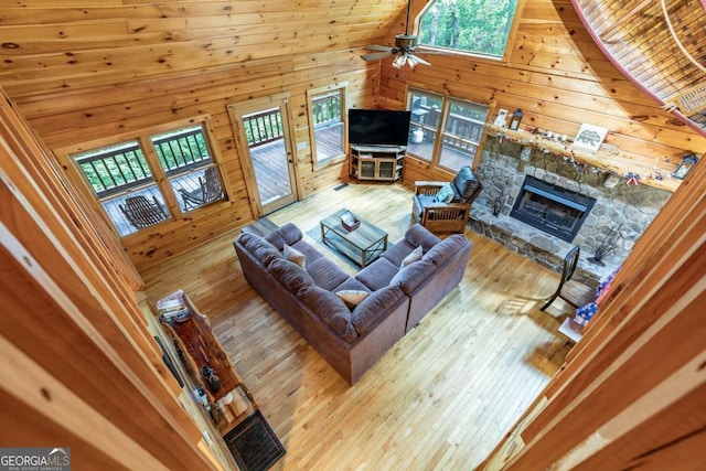 living room featuring ceiling fan, a fireplace, high vaulted ceiling, and light hardwood / wood-style flooring