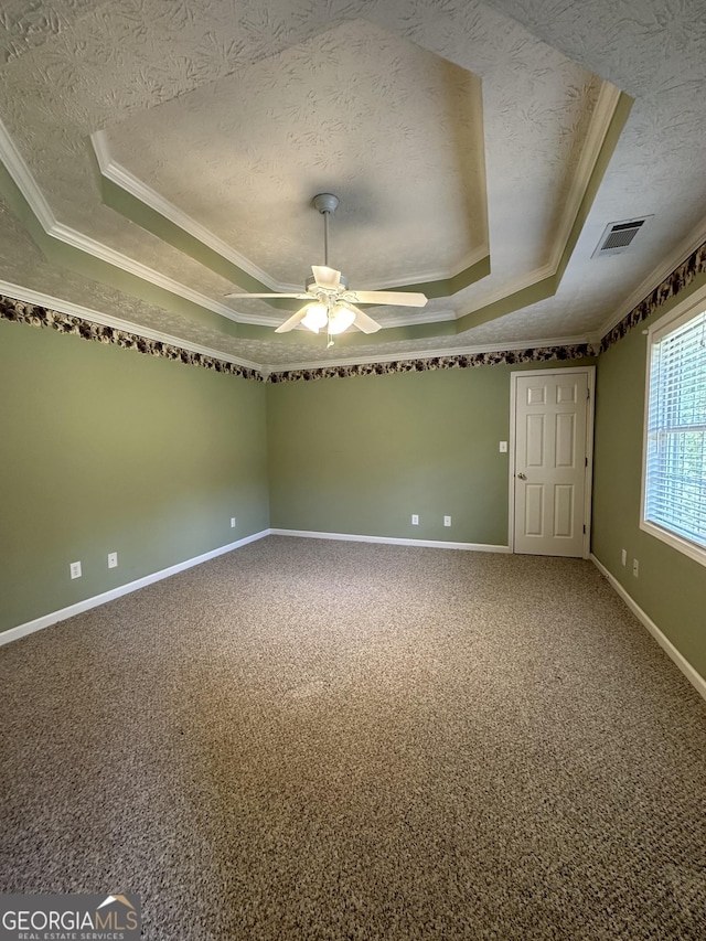 carpeted spare room with a textured ceiling, a raised ceiling, ceiling fan, and ornamental molding