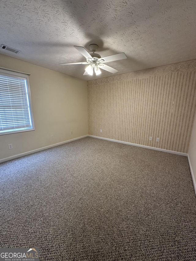 empty room featuring ceiling fan, carpet floors, and a textured ceiling