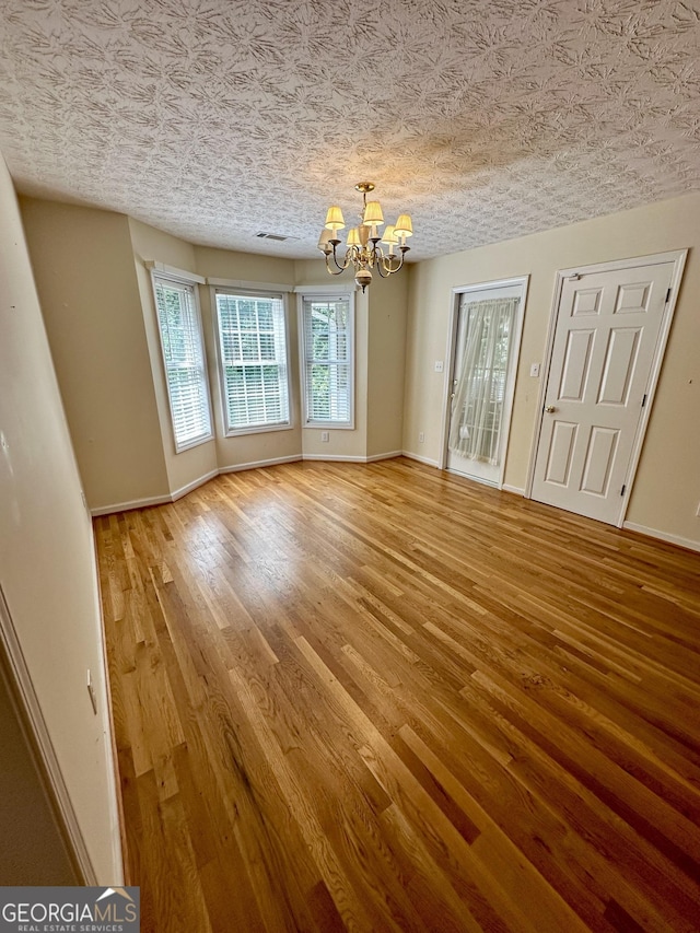 interior space with a chandelier, hardwood / wood-style floors, and a textured ceiling