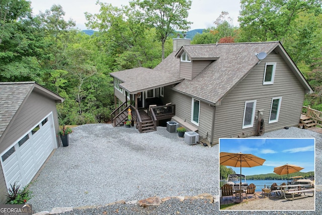 view of front of property with a deck with water view, central AC unit, and a garage