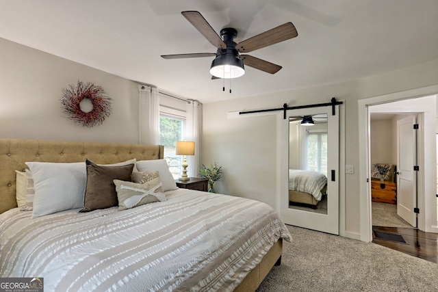 carpeted bedroom with ceiling fan, a barn door, and multiple windows