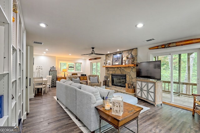 living room with hardwood / wood-style floors, ceiling fan, and a stone fireplace