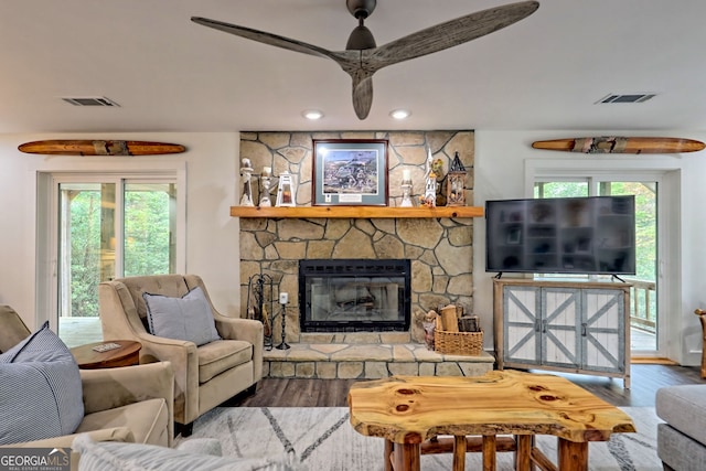 living room featuring a wealth of natural light, ceiling fan, a fireplace, and wood-type flooring