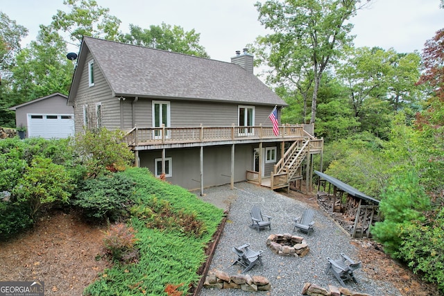 rear view of house with a garage, a deck, and an outdoor fire pit