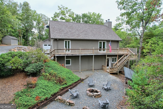 rear view of property featuring a fire pit, a storage shed, and a wooden deck