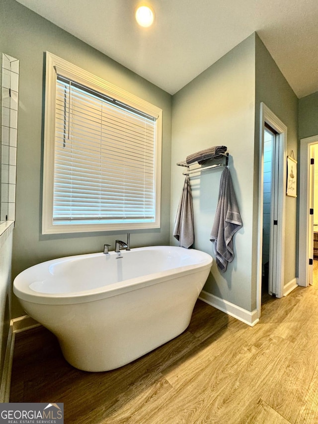 bathroom with wood-type flooring and a tub