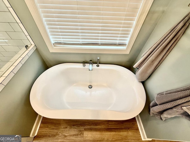 bathroom featuring wood-type flooring and a tub