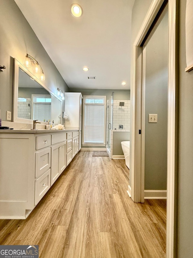 bathroom featuring hardwood / wood-style flooring, vanity, plenty of natural light, and walk in shower