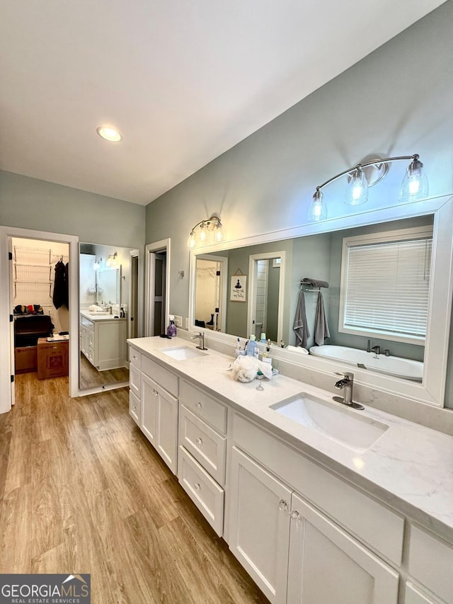 bathroom featuring hardwood / wood-style floors, vanity, and a tub to relax in