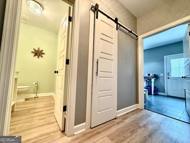 corridor featuring a barn door and light hardwood / wood-style floors