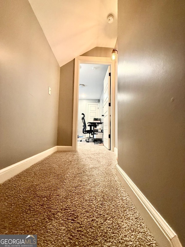 hallway featuring carpet flooring and lofted ceiling