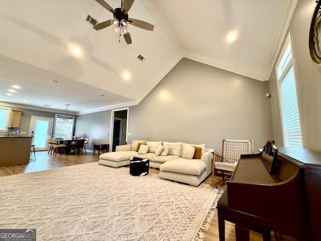 living room featuring ceiling fan, light hardwood / wood-style floors, lofted ceiling, and ornamental molding