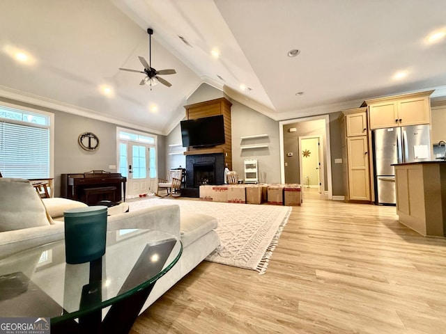 living room featuring ceiling fan, crown molding, light hardwood / wood-style floors, lofted ceiling, and a fireplace