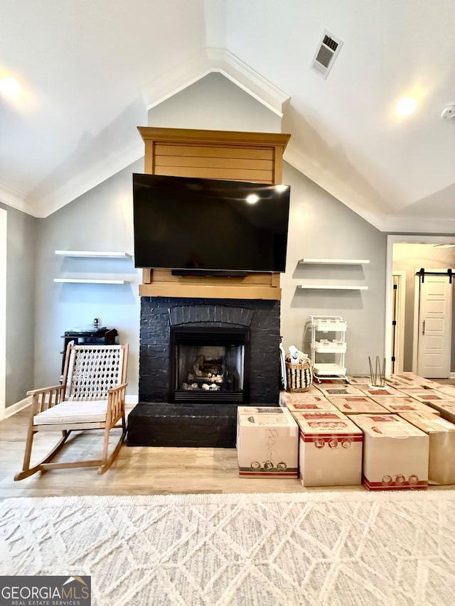 sitting room with crown molding, wood-type flooring, a fireplace, and vaulted ceiling