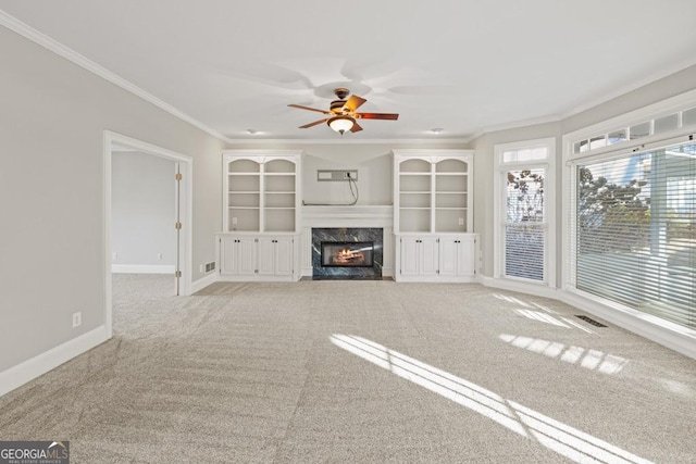 unfurnished living room with light colored carpet, ceiling fan, crown molding, and a premium fireplace