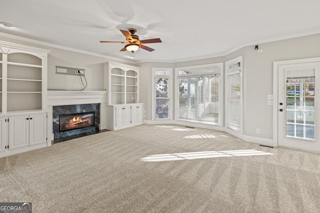 unfurnished living room with ceiling fan, a fireplace, light colored carpet, and crown molding