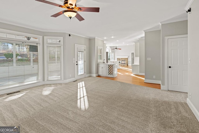 carpeted empty room featuring a healthy amount of sunlight, ceiling fan, and crown molding