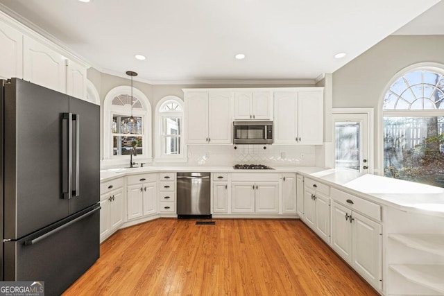 kitchen featuring decorative light fixtures, stainless steel appliances, white cabinetry, and sink